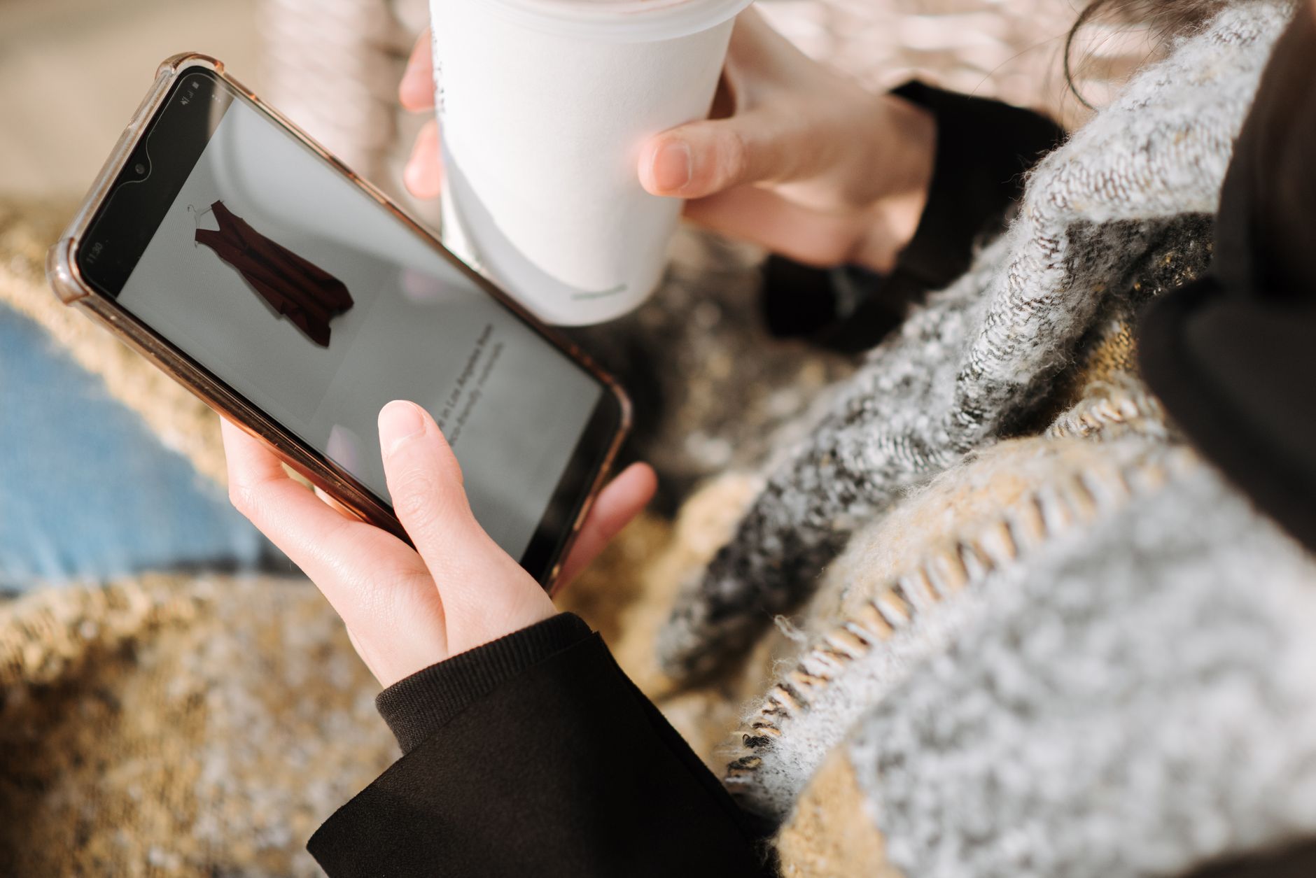 Young woman scrolling on her phone, illustrating doom spending UK impulse buying behaviour